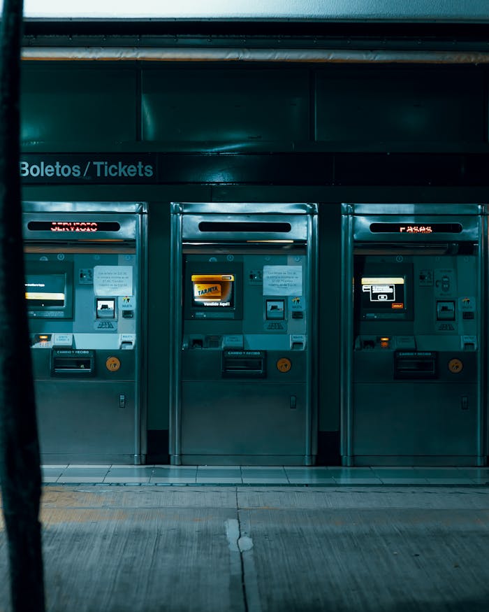 Three ticket vending machines in a dimly lit subway station, emphasizing modern urban technology.