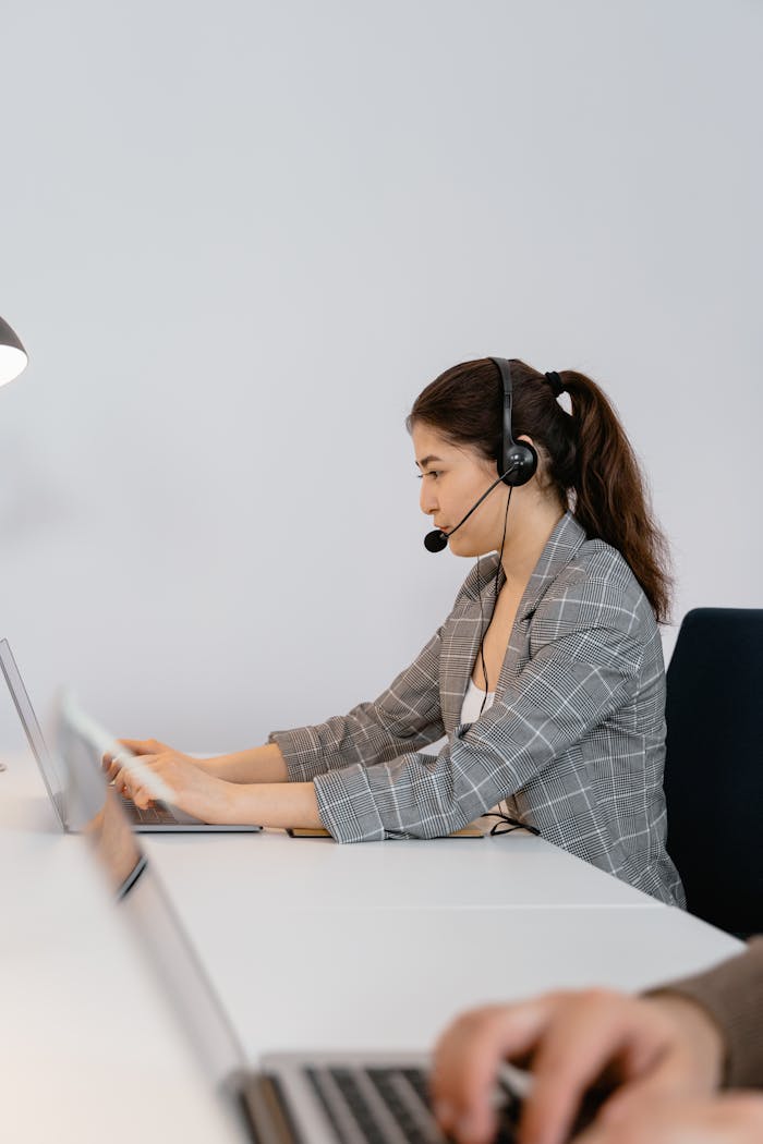 Focused call center agent wearing headphones providing customer support in a modern office.