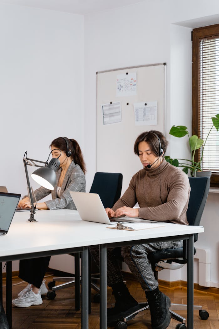 Office call center scene with diverse team using laptops and headsets for customer support.